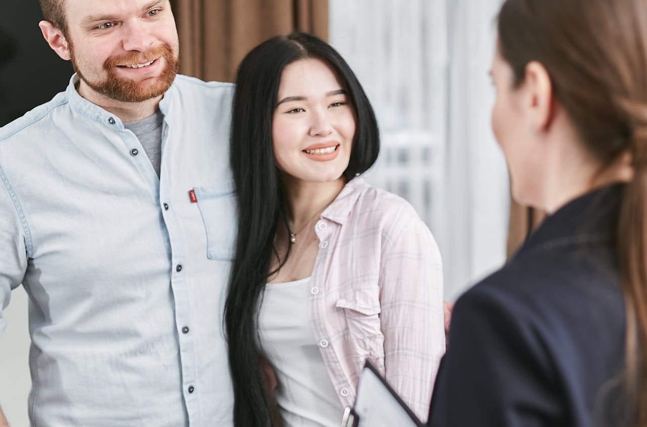 Smiling interracial couple engaging with a professional advisor in an indoor setting.
